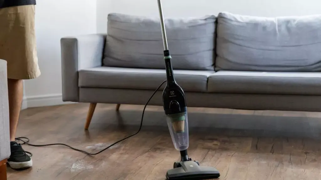 Homem fazendo faxina utilizando aspirador de pó vertical