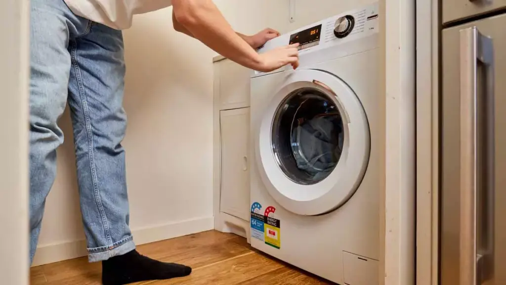 Homem programando uma máquina lava e seca branca