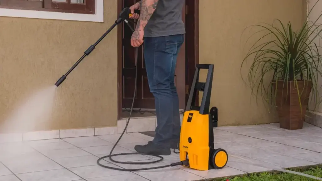 Homem lavando quintal com lavadora de alta pressão