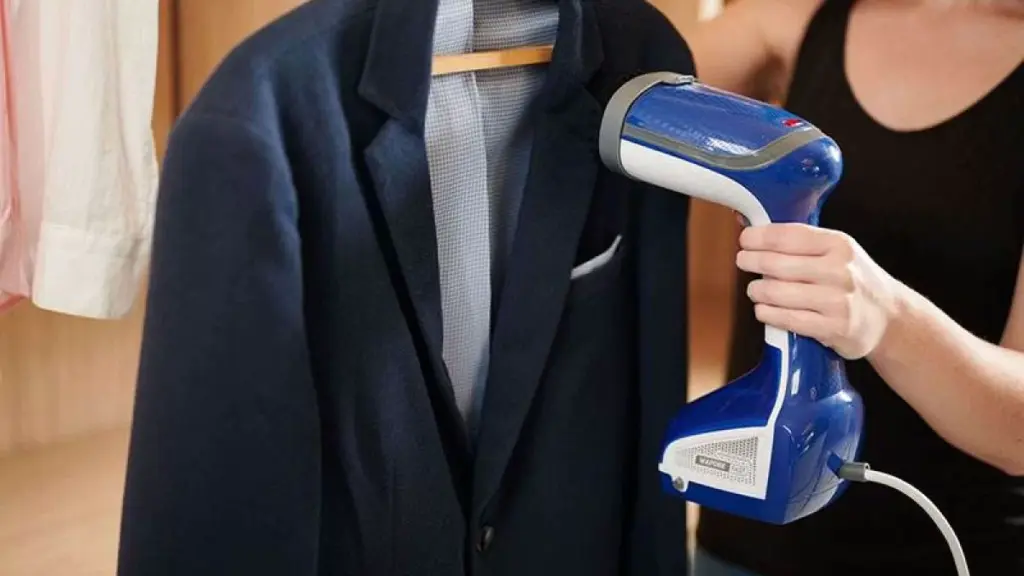 Homem usando vaporizador de roupas em terno